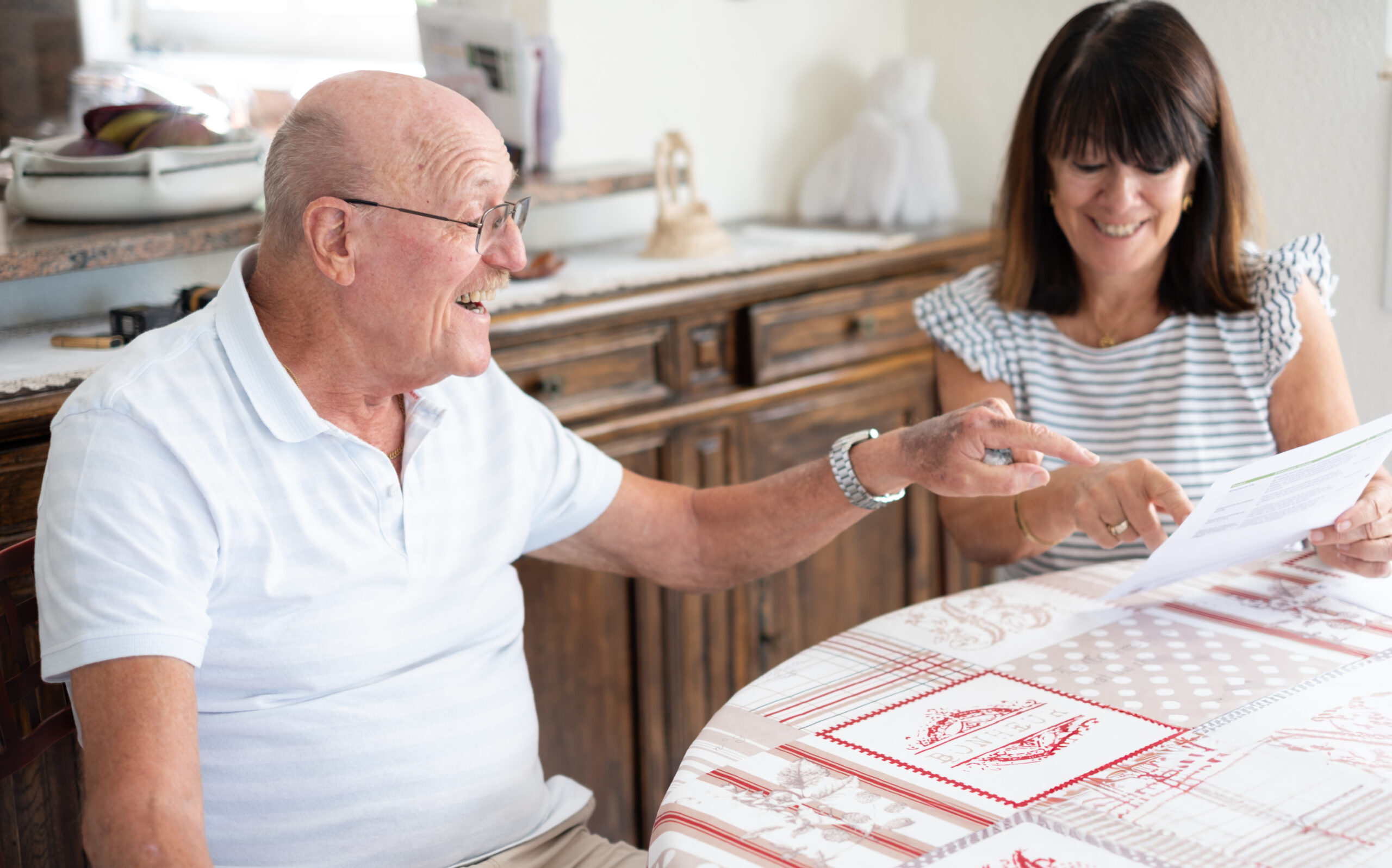 Happy senior couple sitting at home table reading good news from Professional dementia caregiver in Vaughan providing home care to elderly woman with Alzheimer’s