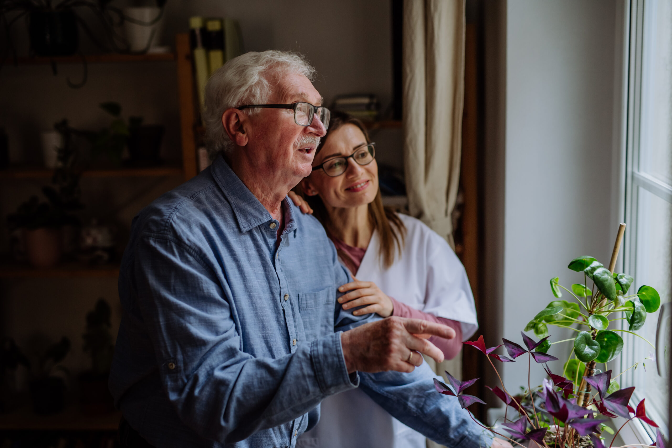 Healthcare worker or caregiver visiting senior man indoors at home, talking. Compassionate Alzheimer’s home care in Concord with a trained caregiver providing memory support and companionship