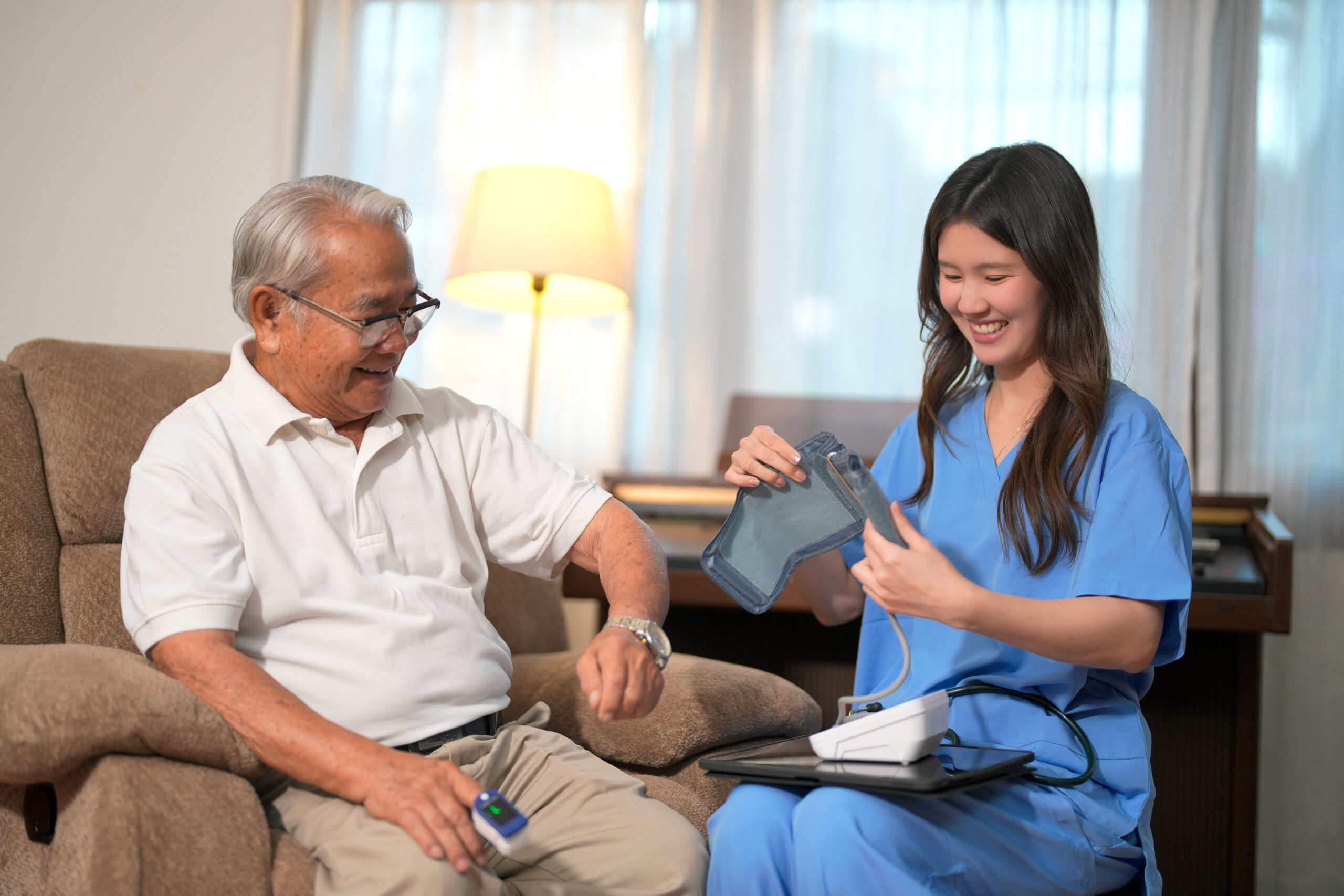 Healthcare worker checks elderly man’s health at home with medical device during daytime Caregiver from a home caregiver agency in Aurora assisting a senior woman with personalized home care services.
